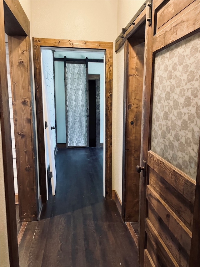 hallway featuring a barn door and dark hardwood / wood-style floors