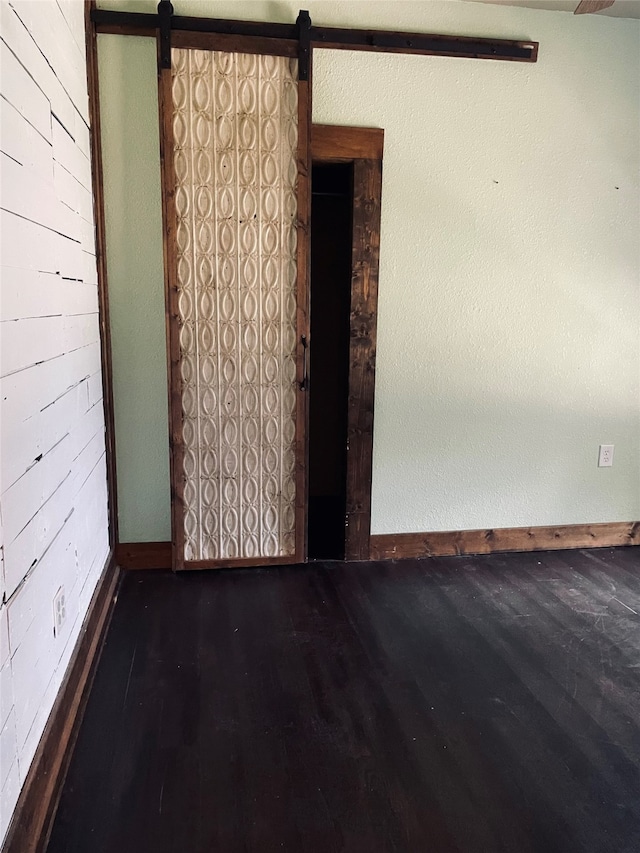 spare room featuring a barn door and dark hardwood / wood-style floors