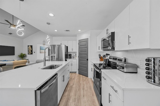 kitchen featuring sink, white cabinetry, hanging light fixtures, appliances with stainless steel finishes, and an island with sink