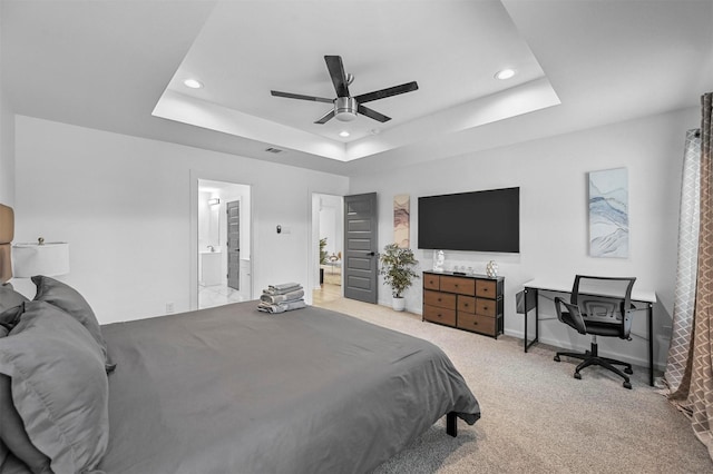 carpeted bedroom featuring ensuite bathroom, ceiling fan, and a tray ceiling