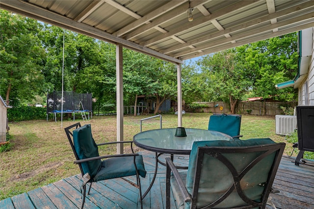 wooden terrace with a lawn, central air condition unit, and a trampoline