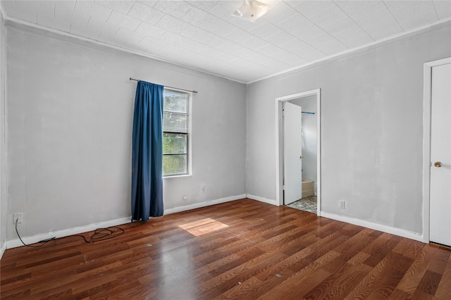 empty room featuring crown molding and dark wood-type flooring