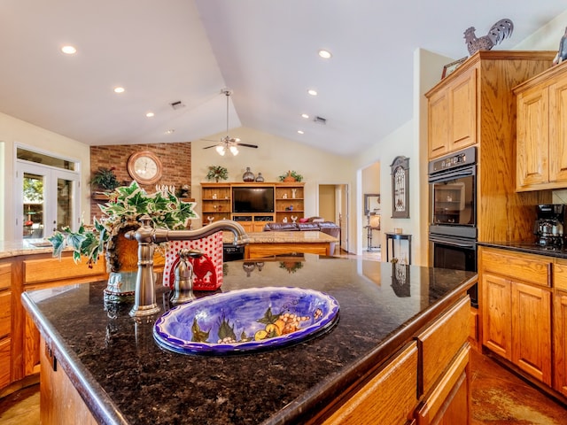 kitchen featuring lofted ceiling, ceiling fan, sink, double oven, and dark stone counters