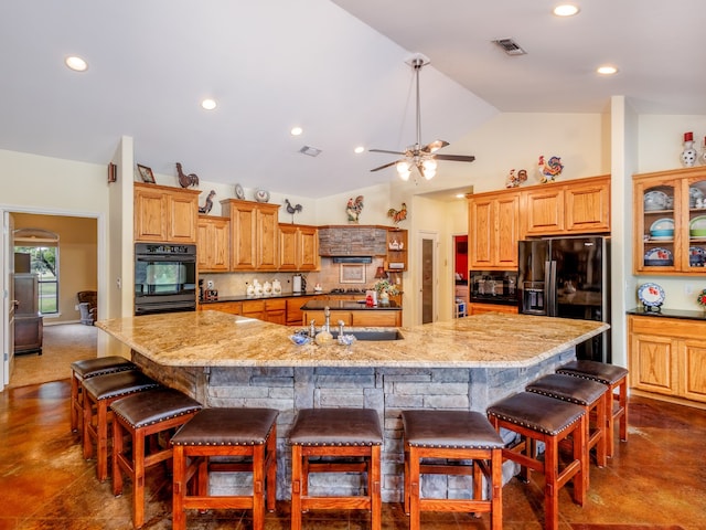 kitchen featuring a spacious island, a kitchen breakfast bar, black appliances, and sink