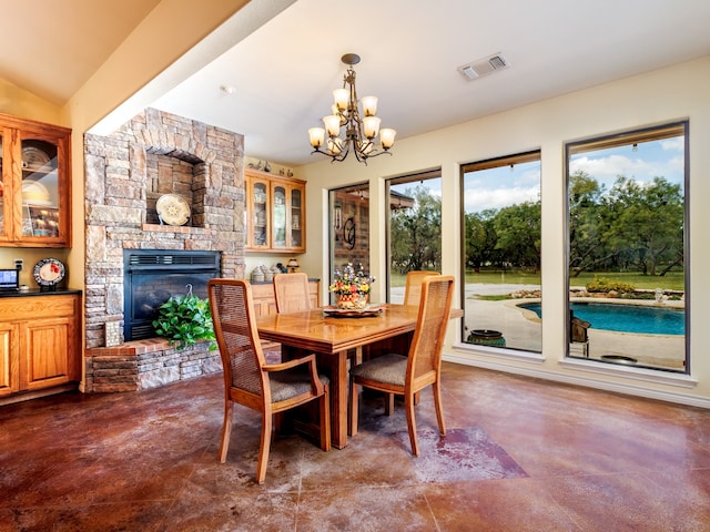 dining space featuring a stone fireplace and a chandelier