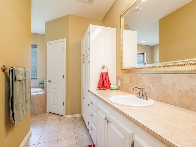 bathroom with tiled bath, vanity, and tile patterned flooring