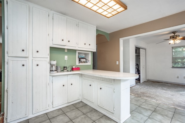 kitchen featuring light tile flooring, ceiling fan, kitchen peninsula, and white cabinets