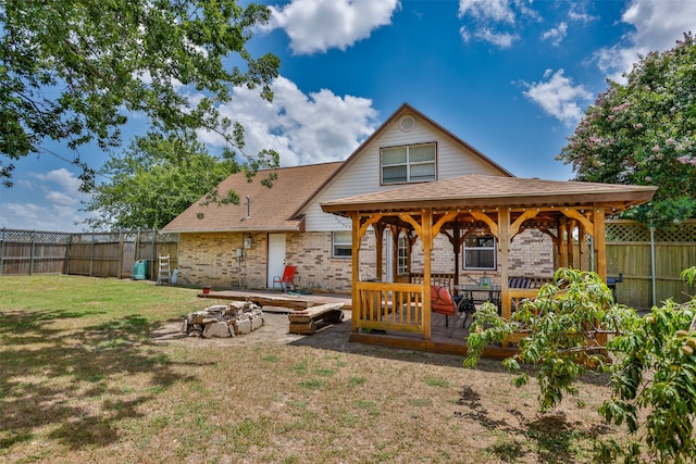 rear view of house featuring a fire pit and a lawn