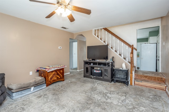 living room featuring ceiling fan and a wood stove