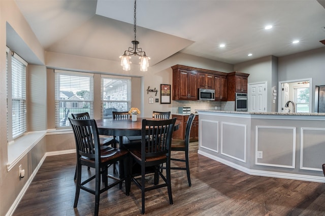 dining room featuring sink, vaulted ceiling, dark hardwood / wood-style floors, and a chandelier