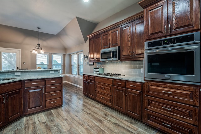 kitchen with stainless steel appliances, light stone countertops, dark brown cabinets, and hanging light fixtures