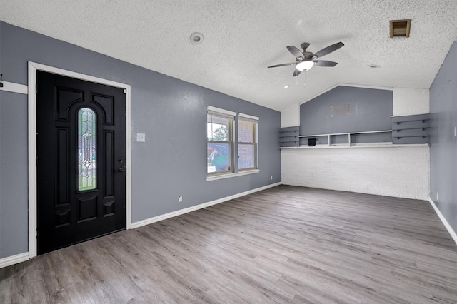 foyer with hardwood / wood-style flooring, a textured ceiling, vaulted ceiling, and ceiling fan