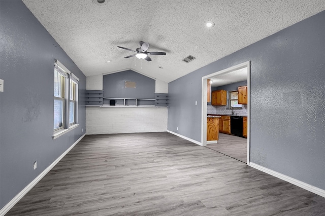 unfurnished living room featuring lofted ceiling, a textured ceiling, ceiling fan, and wood-type flooring