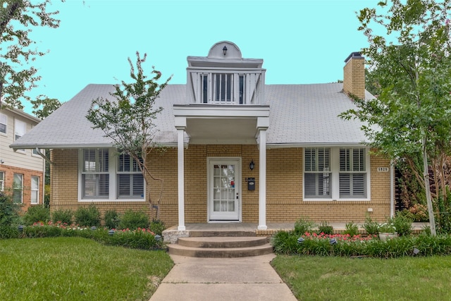 view of front of property featuring a front lawn, a porch, and a balcony