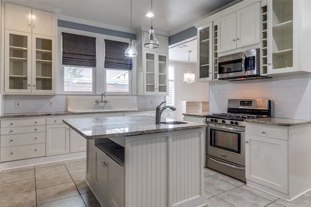 kitchen with appliances with stainless steel finishes, a kitchen island with sink, sink, white cabinets, and light tile patterned flooring