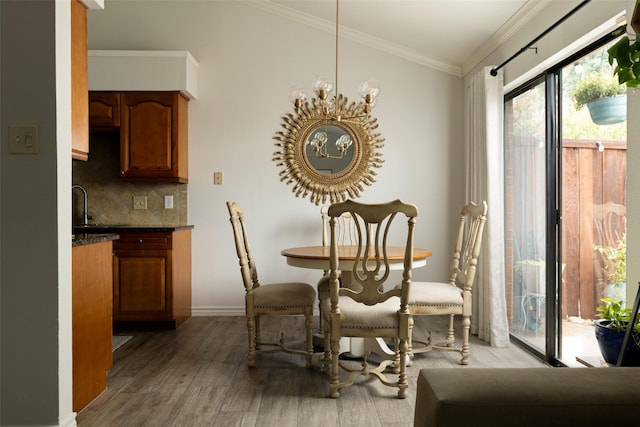 dining space with crown molding, a notable chandelier, and light hardwood / wood-style flooring