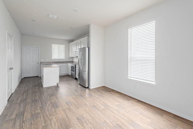 kitchen featuring white cabinets, appliances with stainless steel finishes, a kitchen island, and hardwood / wood-style floors