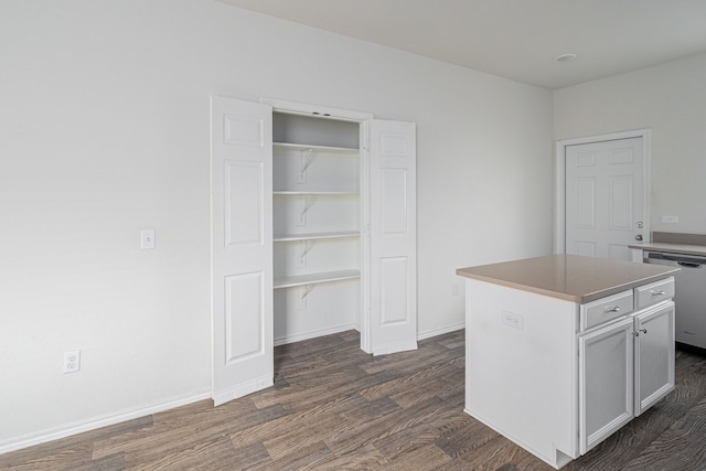 kitchen featuring dark wood-type flooring, a kitchen island, and dishwasher