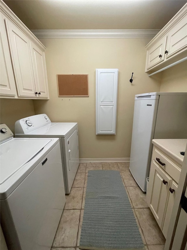 washroom with cabinet space, light tile patterned floors, baseboards, crown molding, and washing machine and dryer