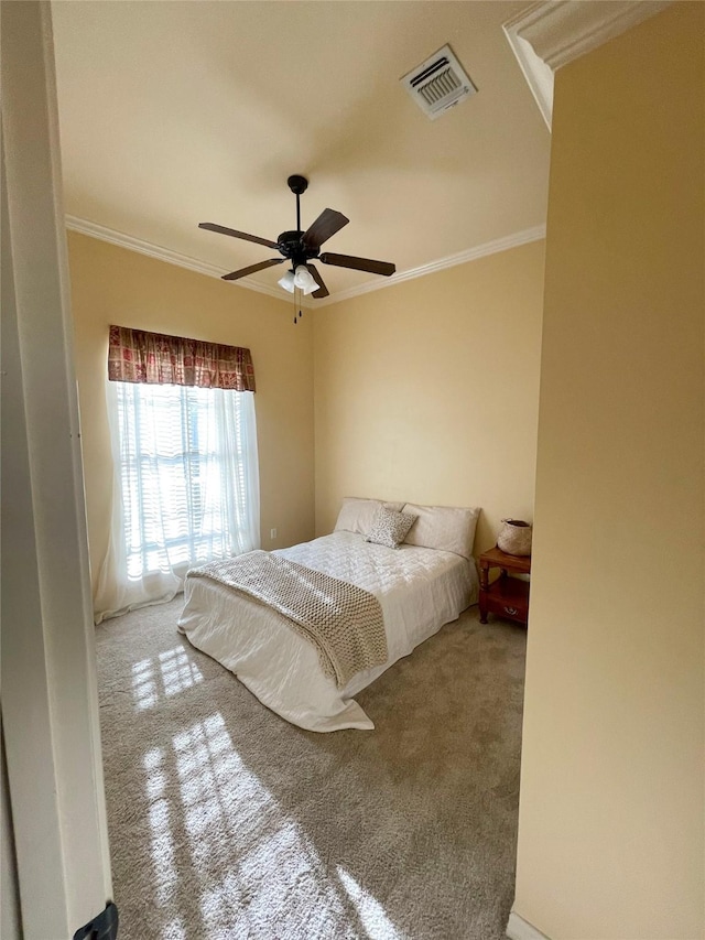 carpeted bedroom with ceiling fan, visible vents, and ornamental molding