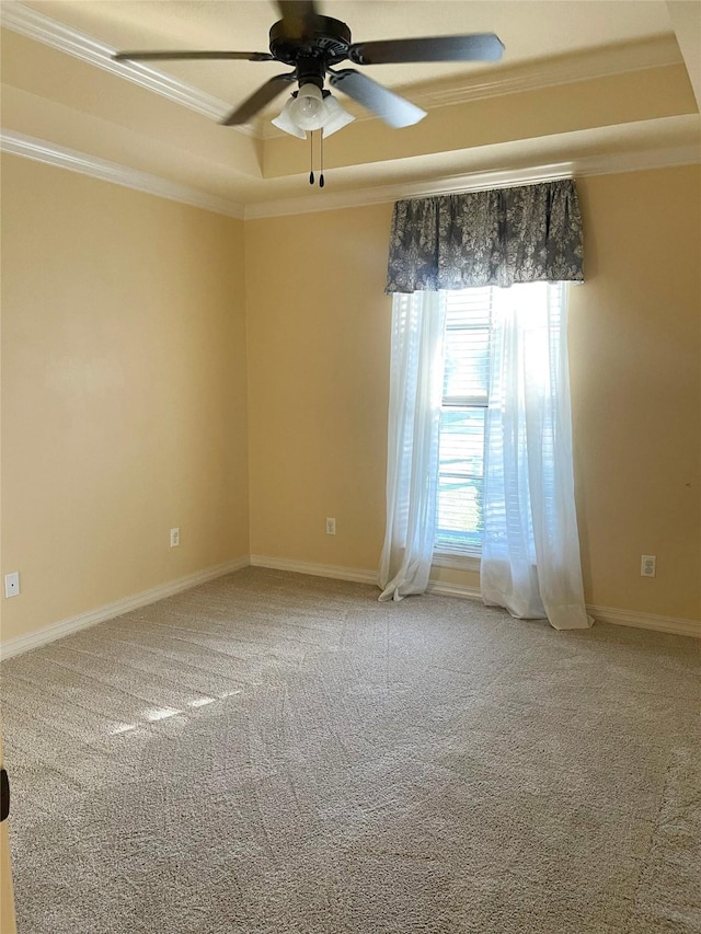 unfurnished room featuring baseboards, a raised ceiling, ceiling fan, ornamental molding, and carpet floors