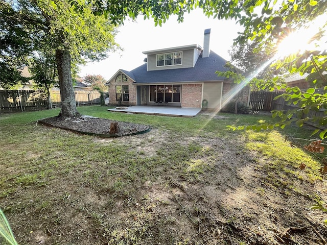 back of house featuring brick siding, a yard, a chimney, a patio, and a fenced backyard