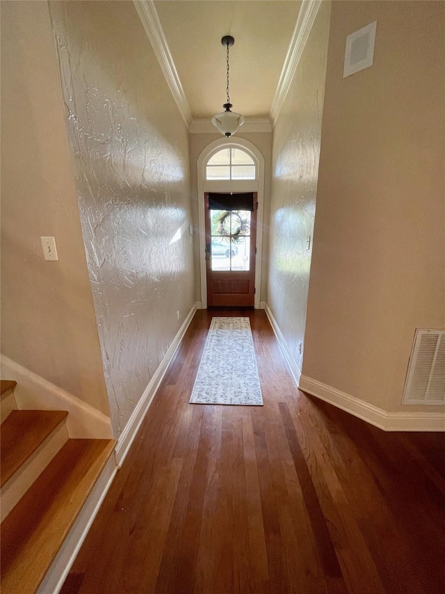 doorway featuring wood finished floors, visible vents, crown molding, and stairs