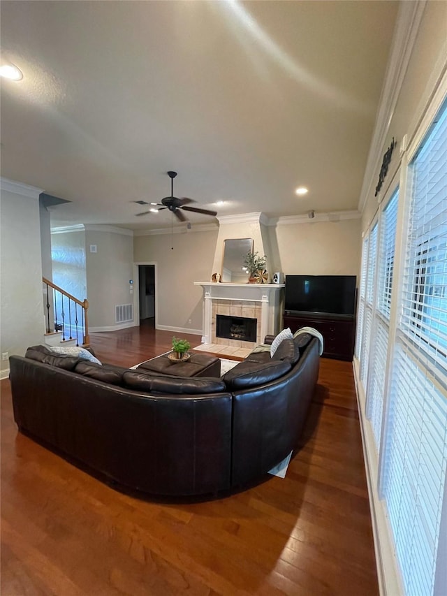 living room featuring visible vents, a tiled fireplace, ornamental molding, a ceiling fan, and wood finished floors