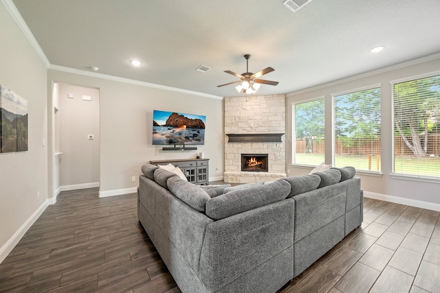 living room with a stone fireplace, ceiling fan, and crown molding