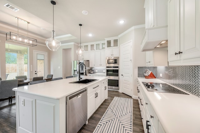 kitchen featuring ornamental molding, white cabinetry, stainless steel appliances, and an island with sink