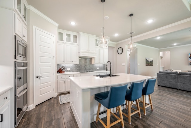 kitchen with white cabinetry, sink, stainless steel appliances, tasteful backsplash, and a kitchen island with sink