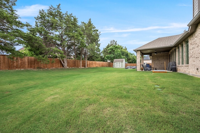 view of yard with ceiling fan and a storage shed