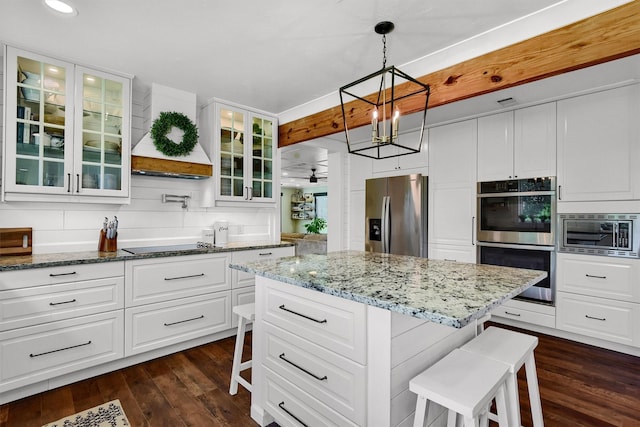 kitchen featuring appliances with stainless steel finishes, dark wood-style flooring, white cabinets, and a kitchen breakfast bar