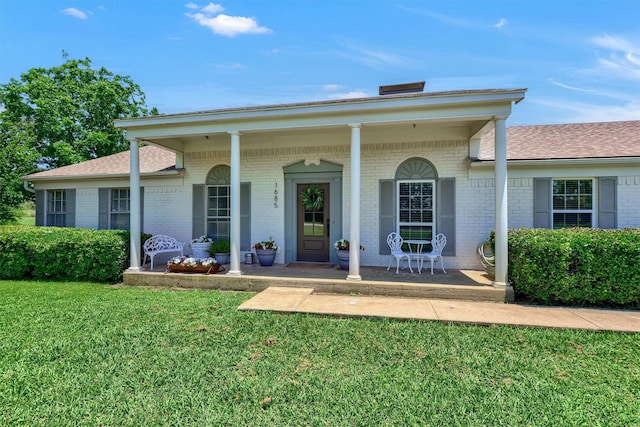 view of front of house featuring brick siding, a front lawn, and a porch