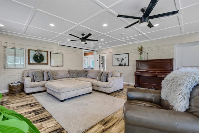 living room featuring coffered ceiling, ceiling fan, hardwood / wood-style floors, and brick wall