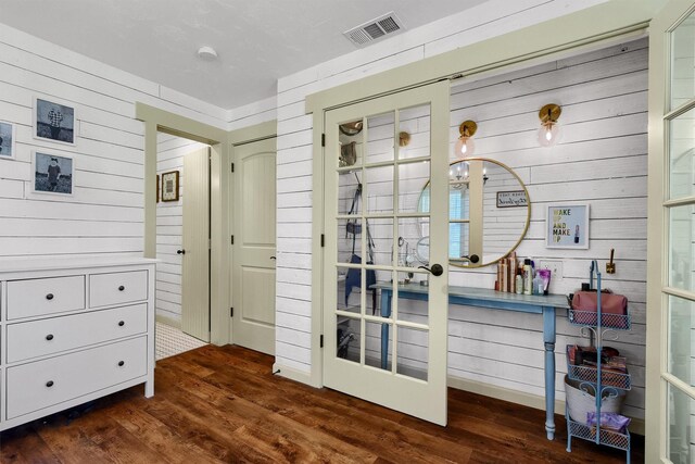 interior space with french doors, dark hardwood / wood-style floors, and wood walls