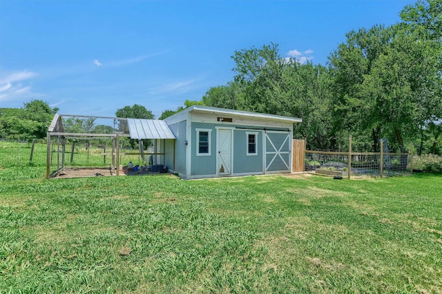 view of outbuilding with a garden, fence, a carport, and an outbuilding