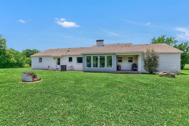 back of property with central AC and a lawn