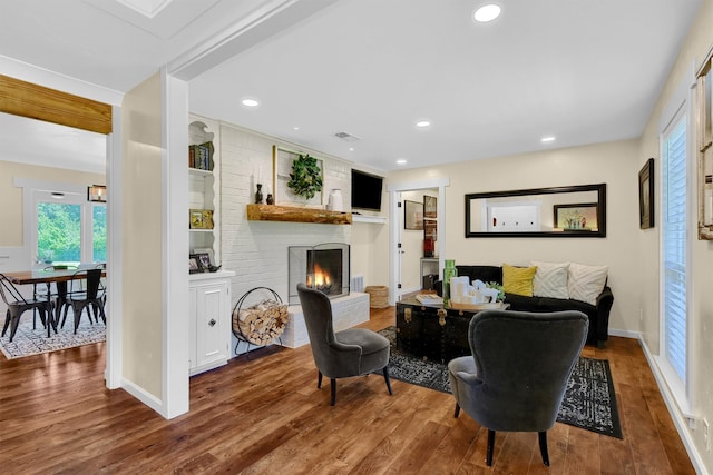 living room featuring brick wall, a brick fireplace, and hardwood / wood-style floors