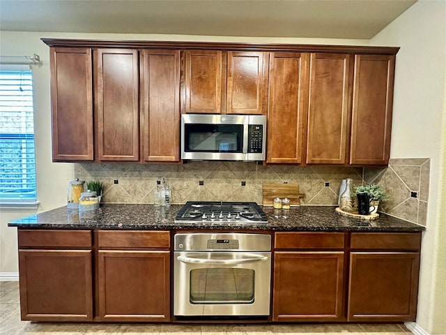 kitchen featuring stainless steel appliances, tasteful backsplash, and dark stone countertops