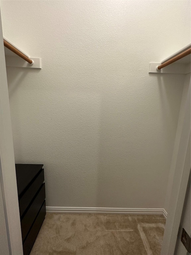 walk in closet with dark carpet