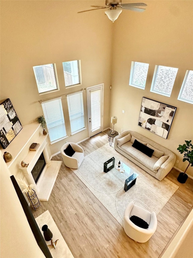 living room with ceiling fan, a high ceiling, and hardwood / wood-style flooring