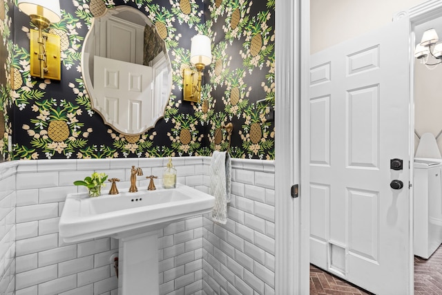 bathroom featuring brick floor, a wainscoted wall, tile walls, and wallpapered walls