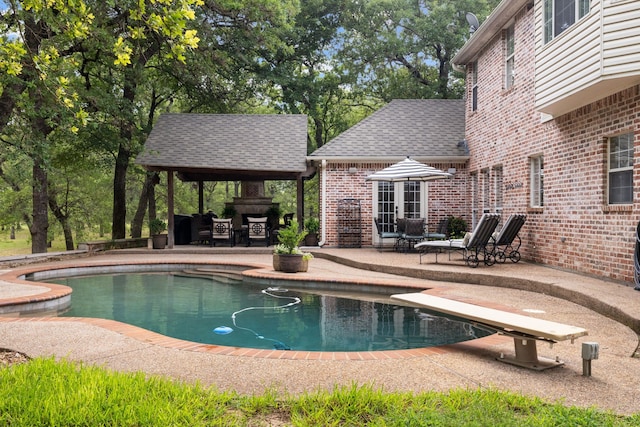 view of pool with a diving board, a fireplace, and a patio