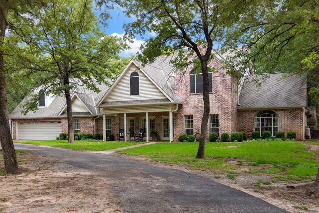 view of front of home with a garage, brick siding, a front yard, and a shingled roof