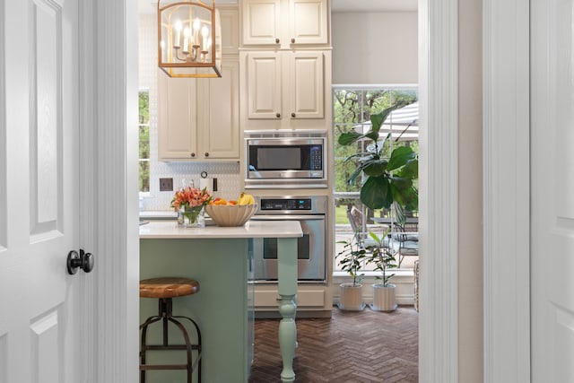 kitchen featuring tasteful backsplash, a breakfast bar, stainless steel appliances, pendant lighting, and an inviting chandelier