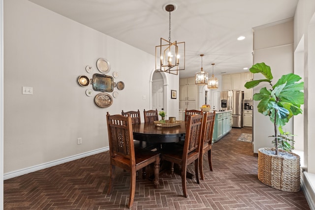 dining room featuring baseboards, arched walkways, and a notable chandelier