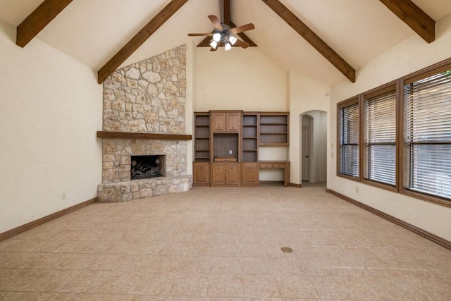 unfurnished living room with a fireplace, beam ceiling, high vaulted ceiling, and ceiling fan