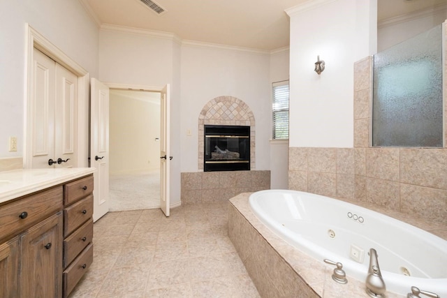 bathroom featuring tiled bath, a tiled fireplace, crown molding, and vanity