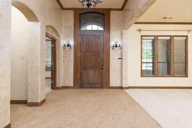 foyer with ornamental molding and an inviting chandelier